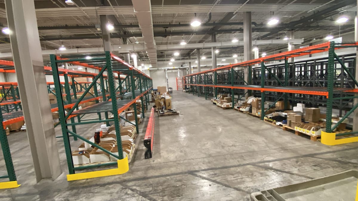 Green and orange selective pallet rack with wire decking and yellow row-end guards in a Las Vegas water district warehouse